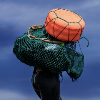 Haenyeo carrying urchin net and float on back facing away from camera